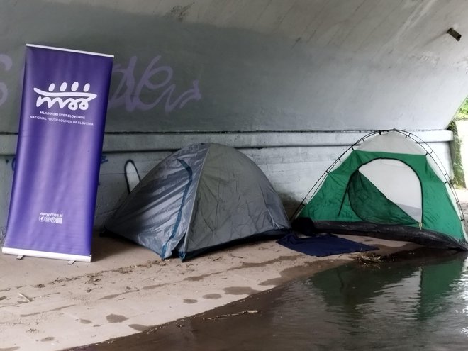 Plakat in šotori MSS pod mostom. FOTO: M. B.