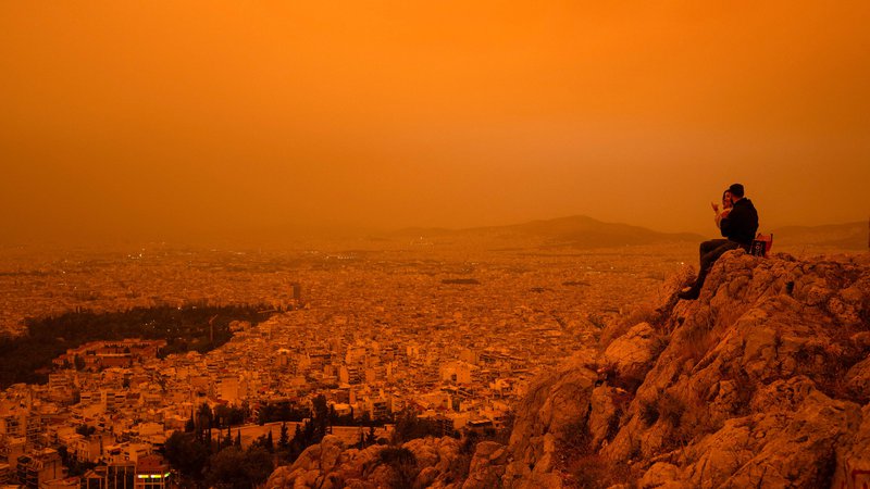 Fotografija: Nad Atene se je spustila dramatična oranžna meglica, ko je veter nad južno Grčijo prinesel tone puščavskega prahu iz afriške Sahare. Po besedah strokovnjakov je to eden najhujših tovrstnih izrednih vremenskih dogodkov, ki so od leta 2018 prizadeli Grčijo. Iz Sahare se na leto dvigne od 60 do 200 milijonov ton puščavskega prahu, večina se hitro spusti na zemljo, majhni delci pa prepotujejo velike razdalje. Foto: Angelos Tzortzinis/Afp
