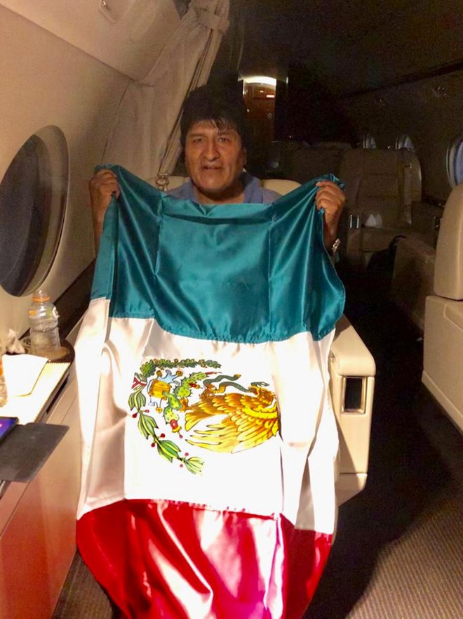 Evo Morales z mehiško zastavo na letalu, ki ga je zanj v La Paz poslala Mehika. FOTO: Reuters