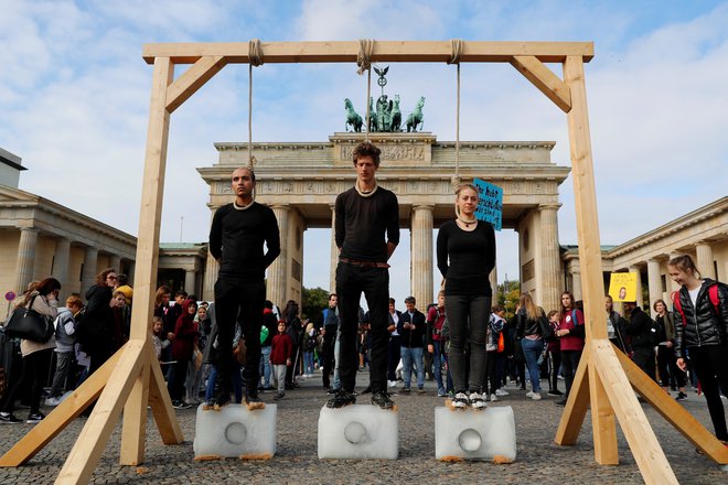 Aktivisti pred Brandenburškimi vrati opozarjajo na segrevanje planeta. FOTO: Fabrizio Bensch/Reuters