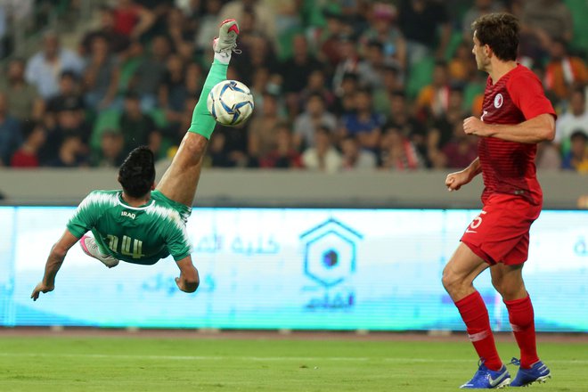 Iračan Amjad Attwan je z atraktivnim poskusom želel zabiti gol. Ni bil uspešen, a je Irak vseeno dosegel prvo kvalifikacijsko zmago pred domačimi navijači v Basri. FOTO: AFP