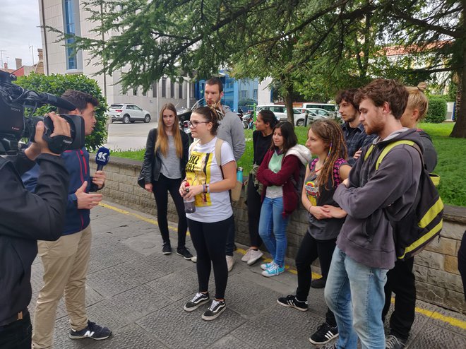 Študentka s plastenko, v kateri je imela črnilo za volilno skrinjico, in skupina študentskih protestnikov daje izjavo za medije.