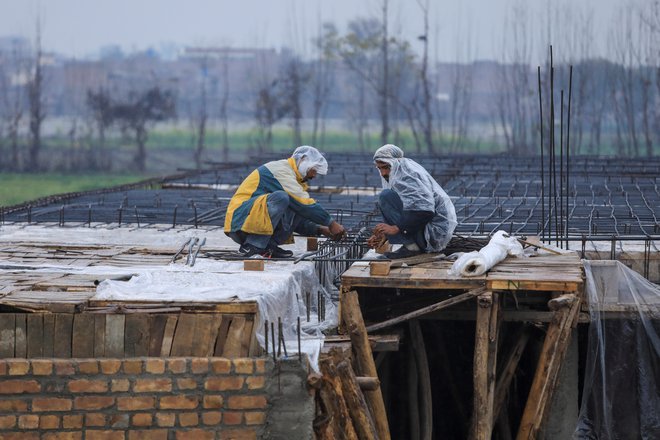 Delavci na prostem so toploto iskali v plastičnih palerinah. FOTO: Fayaz Aziz/Reuters