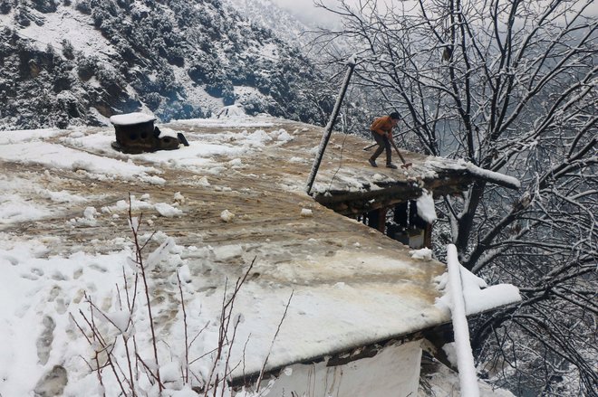 Deček čisti sneg s strehe domače hiše. FOTO: Stringer Reuters