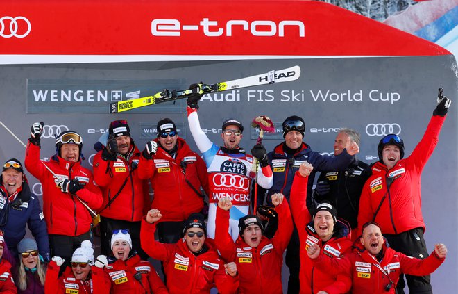 Švicar Beat Feuz na zmagovalnih stopničkah skupaj s svojo ekipo. FOTO: Leonhard Foeger/Reuters