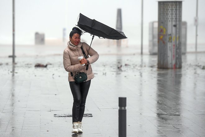 Ženska kljubuje vetru na plaži El Bogatell v Barceloni, ki jo je, kot več drugih španskih obalnih mest, zajela nevihta Gloria z močnim vetrom, dežjem in snegom. FOTO: AFP/Josep Lago