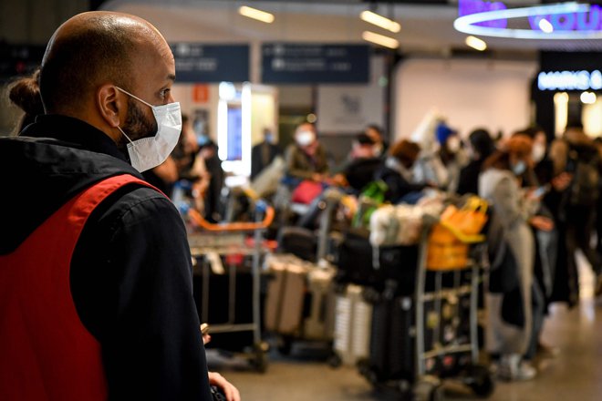 Potnike iz Kitajske na največjem pariškem letališču so včeraj takole sprejemali letališki uslužbenci, opremljeni z maskami. Foto AFP