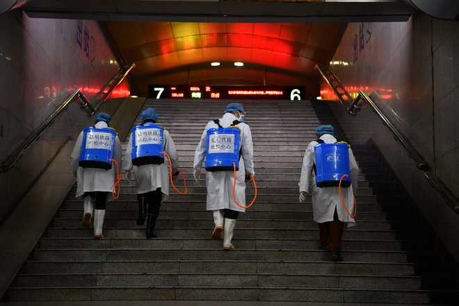 Zdravstveni delavci razkužujejo železniško postajo v mestu Kunming. FOTO: Reuters