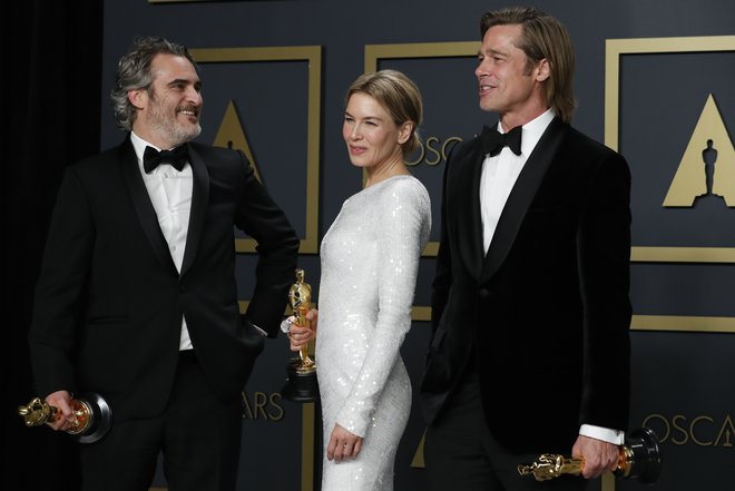 Joaquin Phoenix, Renee Zellweger in Brad Pitt pozirajo z zlatimi kipci. FOTO: Lucas Jackson/Reuters