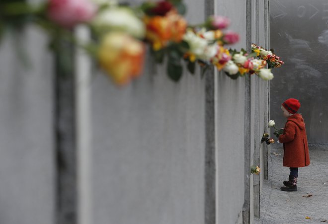 A young girl places a rose at the Berlin Wall memorial in Bernauer Strasse, during a ceremony marking the 25th anniversary of the fall of the Berlin Wall, in Berlin November 9, 2014.        REUTERS/Fabrizio Bensch (GERMANY  - Tags: POLITICS ANNIVERSARY SOCIETY TPX IMAGES OF THE DAY)   - LR1EAB90QXMSK