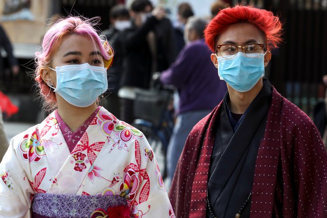 Turisti z maskami v japonski prestolnici. FOTO: Athit Perawongmetha/Reuters