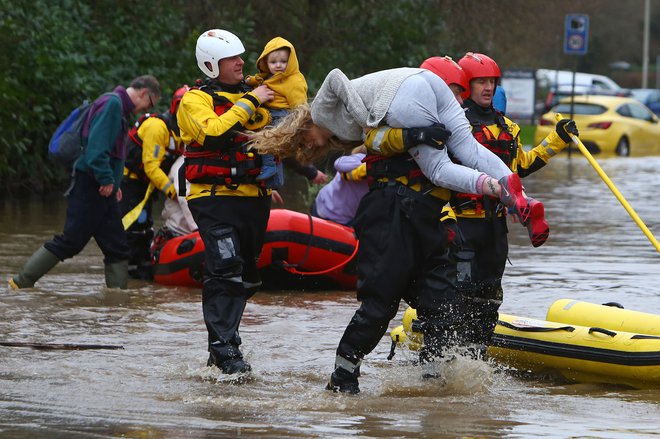 Pripadniki reševalnih služb evakuirajo prebivalce in njihove pse iz poplavljenih hiš z reševalnimi čolni, potem ko je reka Taff&nbsp; prestopila bregove v Nantgarwu, na jugu Walesa. Veliko Britanijo je konec tedna zajela nevihta Dennis s silovitim vetrom in nalivi, ki so povzročili poplave. Oblasti so razglasile nevarnost poplav v več kot 300 krajih, še posebej kritično je na jugu Walesa. FOTO: Geoff Caddick/Afp<br />
&nbsp;