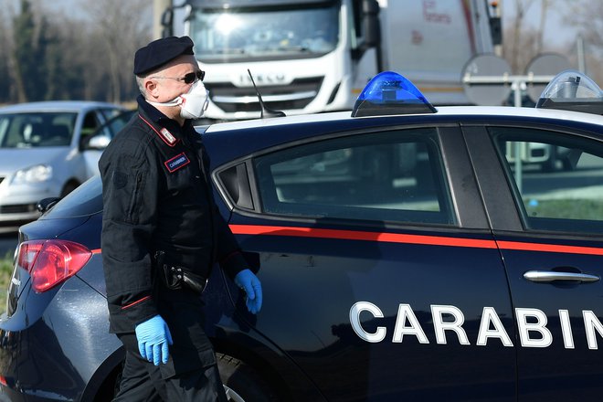 Italijanski karabinjer z masko na policijskem kontrolnem mestu nekaj kilometrov od kraja Castiglione d&#39;Adda, jugovzhodno od Milana. FOTO: Miguel Medina/Afp