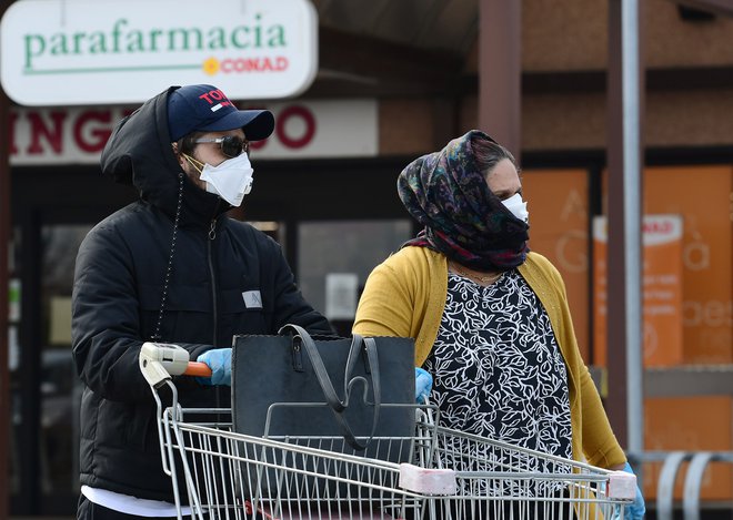 V mesto Casalpusterlengo v severni Italiji, ki je zaradi izbruha virusa zaprto v karenteno, ljudje v vrstah stojijo pred trgovinami z živili. FOTO: Miguel Medina(AFP