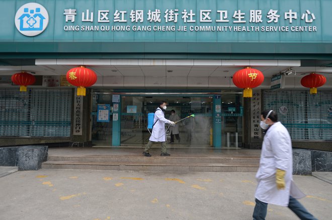Delavec dezinficira vhod v bolnišnico v Wuhanu. FOTO: Reuters