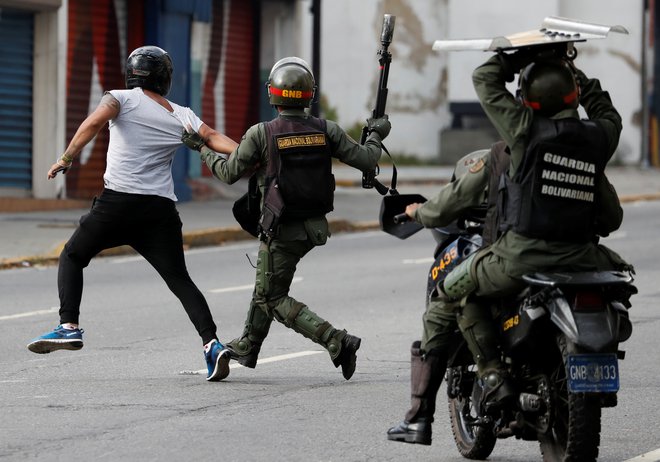 Pripadniki venezuelskih varnostnih sil lovijo protestnika med januarskimi protivladnimi demonstracijami v Caracasu, med katerimi je bilo pridržanih 740 ljudi. FOTO: Reuters