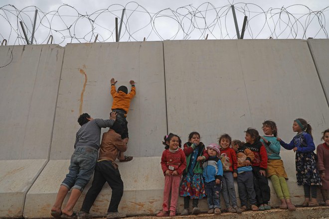 Otroški begunci, ujeti na severu Sirije, poskušajo preplezati zid, ki ga je Turčija postavila na meji, da bi preprečila prihod beguncev iz Sirije. FOTO: Aaref Watad/AFP