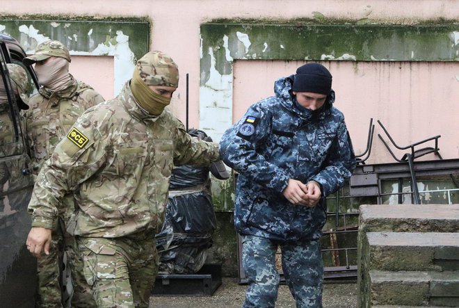 Član ruske Zvezne varnostne službe (FSB) vodi ukrajinskega mornarja na zaslišanje.&nbsp;FOTO: Pavel Rebrov/Reuters