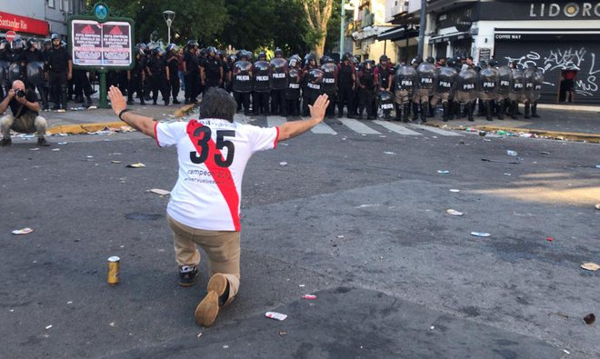 Navijač Riverja prosi policiste, naj se ga usmilijo. Policisti so namreč pretepli tudi številne navijače, ki niso naredili nič spornega. FOTO: AFP