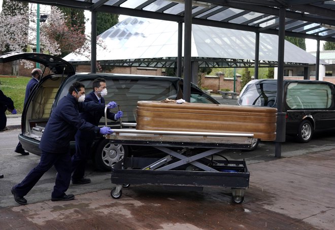 Zaradi pomanjkanja zaščitne opreme madridska pogrebna podjetja ne bodo več prevažala umrlih za koronavirusom. Na posnetku eden zadnjih prevozov včeraj v krematorij v Madridu. FOTO: Juan Medina/Reuters