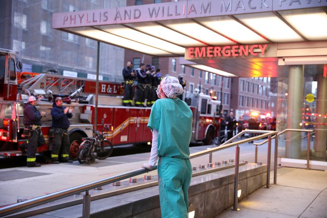 Gasilci se z aplavzom zahvaljujejo naporom zdravstvenega osebja na pavilijonu Phyllis And William Mack na Manhattanu v New Yorku, kjer so razmere na področju koronavirusa zadnje dni zelo, zelo težke. Foto Reuters