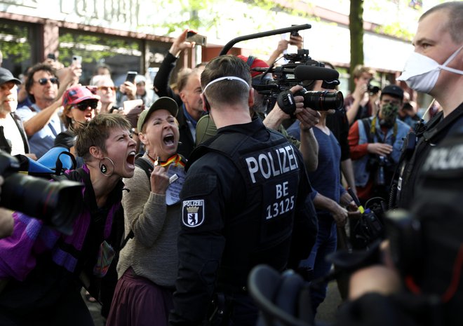 V Berlinu ljudje kričijo na policiste med protestom teoretikov zarote, medtem ko drugi protestniki protestirajo proti karanteni, ki je bila uvedena za upočasnitev širjenja koronavirusa. FOTO: Christian Mang/Reuters