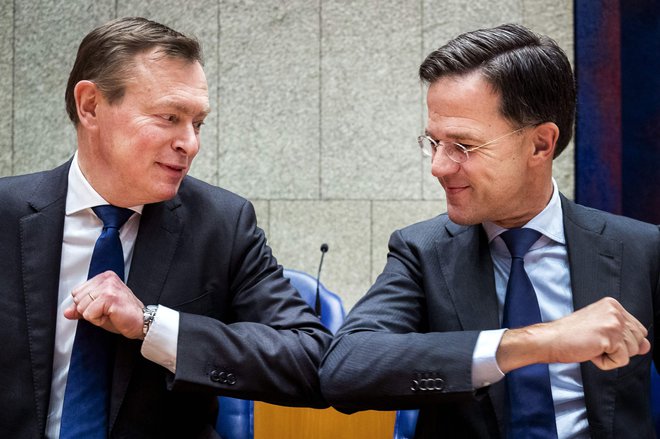 Nizozemski premier Mark Rutte (desno), nizozemski minister za zdravstveno oskrbo Bruno Bruins in njun pozdrav s komolci med sejo spodnjega doma nizozemskega parlamenta. Foto: Remko De Waal/Afp