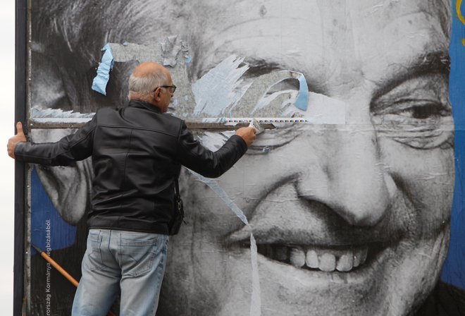 Activists of Egyutt (Together) opposition party removes a government billboard displaying George Soros in monochrome next to a message urning Hungarians to take part in a national consultation about what it calls a plan by the Hungarian-born financier to settle a million migrants in Europe per year, in Budapest, Hungary, October 5, 2017. REUTERS/Bernadett Szabo - RC150C929800