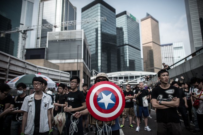Osredotočenje kitajske na Ameriko pomeni pripravljanje na spopad okoli Tajvana. Na fotografiji protestniki proti Kitajski v Hongkongu z emblemom junaka iz stripov Stotnika Amerike. FOTO:&nbsp;Philippe Lopez/Afp