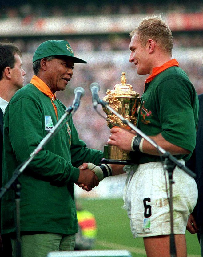 Poseben trenutek v zgodovini Južne Afrike predstavlja slovesna razglasitev svetovnih prvakov v ragbiju 1995, ko je Nelson Mandela predal pokal domačemu kapetanu Francoisu Pienaarju. FOTO: Reuters