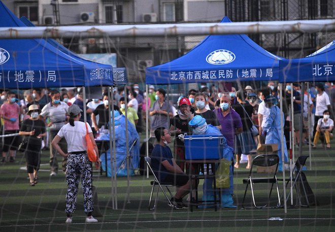 Zdravstveni delavci nosijo zaščitne obleke med testiranjem ljudi, ki so obiskali tržnico Ksinfadi v Pekingu. Tam naj bi se okužilo 36 ljudi. FOTO: Noel Celis/AFP