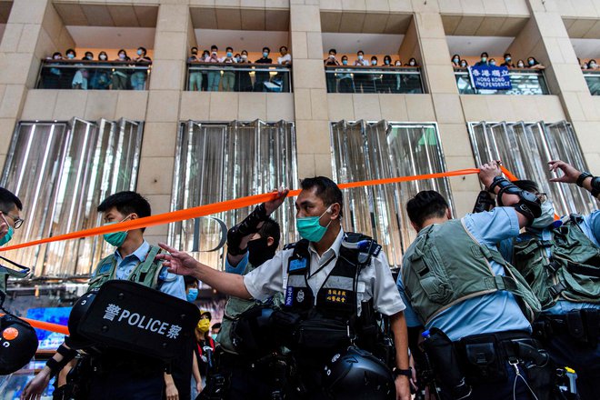 Policijsko preiskovanje trgovskega centra v Hongkongu, kjer ljudje čakajo na začetek današnjega protesta. FOTO: Anthony Wallace/AFP