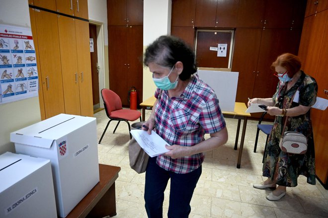 Parlamentarnih volitev na Hrvaškem se je danes do 16.30 udeležilo 34,04 odstotka volivcev, je sporočila hrvaška državna volilna komisija na svoji spletni strani. FOTO: Denis Lovrovic/AFP