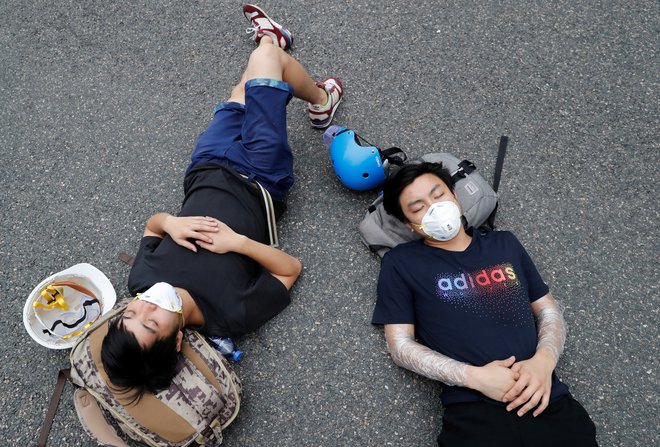 Protestniki, ki so taborili čez noč, spijo ob cesti v bližini stavbe zakonodajnega sveta, sredi demonstracij proti izročitvi v Hongkongu. FOTO: Jorge Silva/Reuters