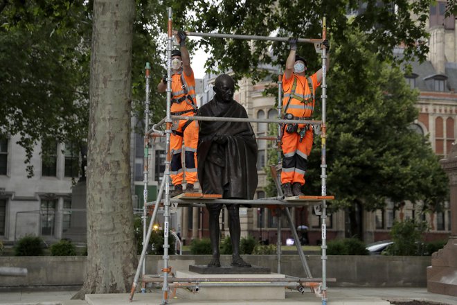 Potem ko so v Amsterdamu kip Gandhija premazali z barvo in popisali z grafiti, so oblasti v Londonu kip indijskega politika in aktivista iz previdnosti zaščitile. Foto Matt Dunham/AP