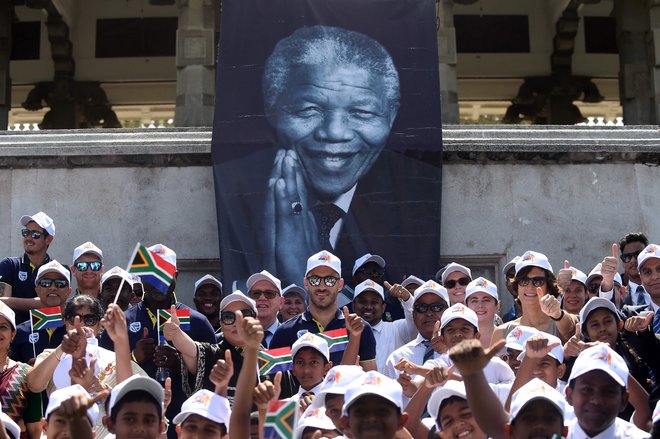 Člani južnoafriške reprezentance kriketa na slovesnosti ob 100. obletnici rojstva Mandele pozirajo z otroki. FOTO: Ishara S. Kodikara/AFP