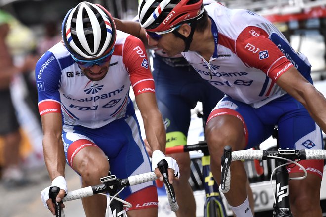France's Thibaut Pinot (L) is comforted by a teammate as he suffers pain in his left leg during the nineteenth stage of the 106th edition of the Tour de France cycling race between Saint-Jean-de-Maurienne and Tignes, in Tignes, on July 26, 2019. (Phot