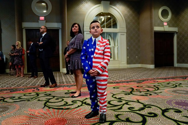 9-year-old Reed Elliotte stands in the back of the room in a U.S. flag outfit with his mother Larrietta listening to U.S. President Donald Trump address the AMVETS American Veterans convention in Louisville, Kentucky U.S. August 21, 2019.   REUTERS/Kevin Lamarque     TPX IMAGES OF THE DAY - RC1229D84E20