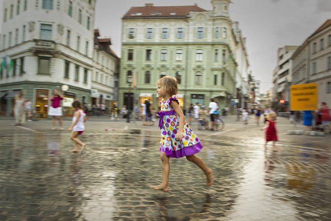 Na Prešernovem trgu v Ljubljani, kjer se v umetnem dežju lahko ljudje malo ohladijo. Foto Voranc Vogel