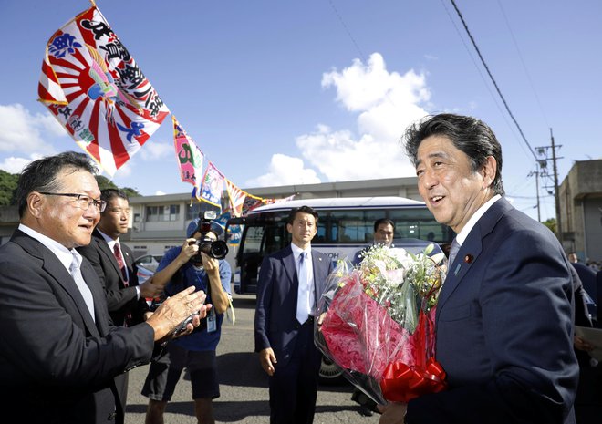 Japonski premier Šinzo Abe je dobil šopek cvetja, ko je sporočil, da bo še tretjič kandidiral za predsednika vladajoče Liberalnodemokratske stranke. FOTO: Reuters