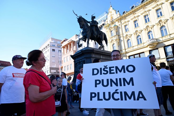 Protestnica s transparentom "Dihamo s polnimi pljuči" na protestu v Zagrebu. FOTO: Denis Lovrovic/AFP
