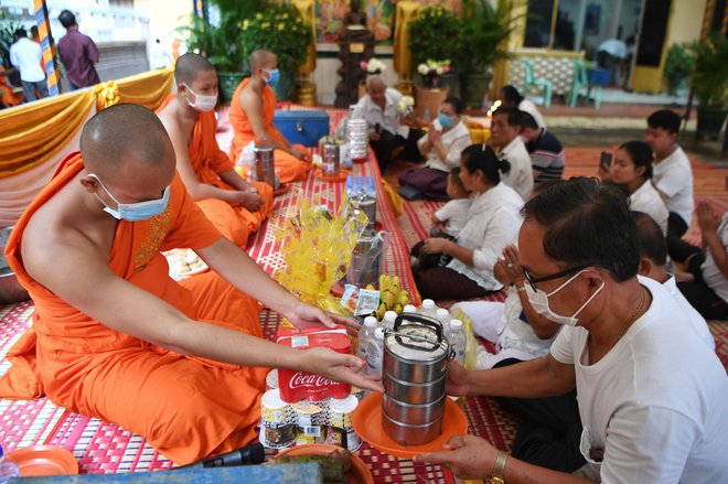 V pagodi v Phnom Penhu menihi sprejemajo hrano. FOTO: Tang Chhin Sothy/AFP