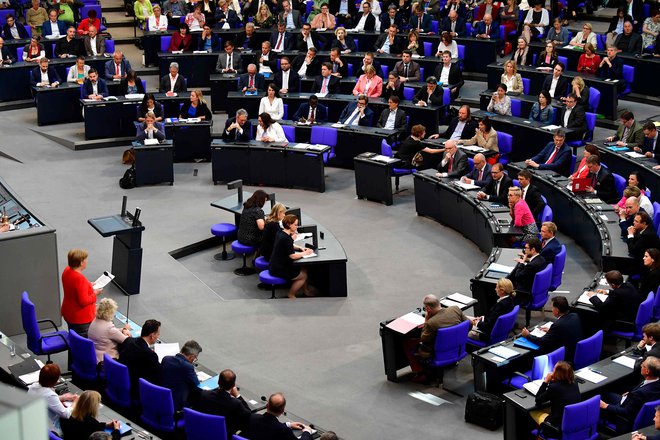 Kanclerka Angela Merkel (levo spodaj v rdečem suknjiču) med odgovarjanjem na vprašanja poslancev v bundestagu. FOTO: AFP