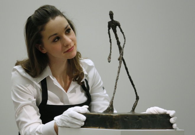 Ena zaposlenih pri Sotheby&#39;s ob kipcu Alberta Giacomettija pred dražbo v Londonu. FOTO: Reuters Reuters