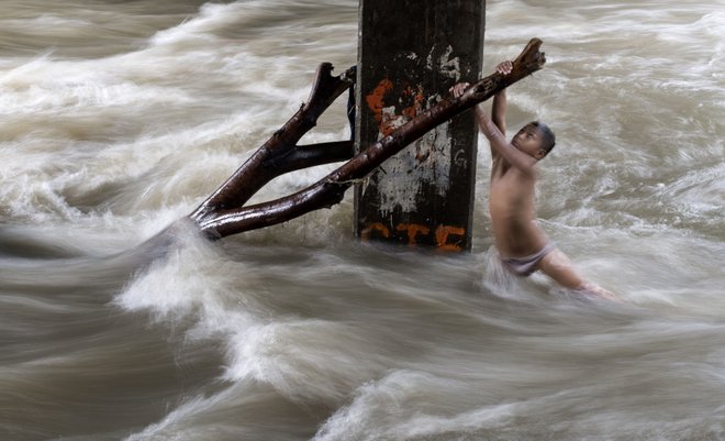 Po hudem nalivu so reke v Manili precej narasle, kar pa otrok ni odvrnilo od igranja in kopanja v njej. FOTO: Noel Celis/AFP