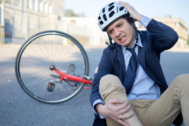 Aching man after bicycle accident on the asphalt
