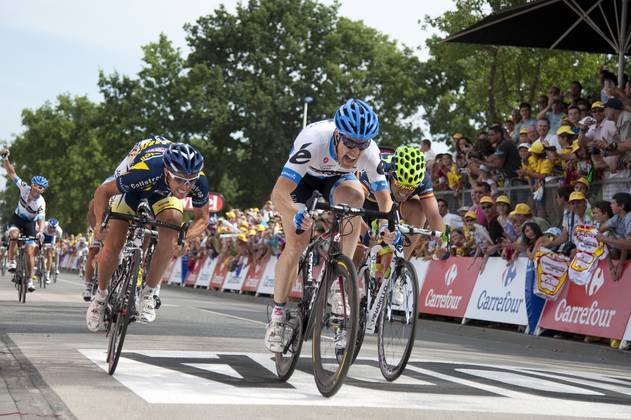 US Tyler Farrar (C) sprints as he crosses the finish line with second-placed France's Romain Feillu (L) and third-placed Spain's Jose Joaquin Rojas (R) at the end of the 198 km and third stage of the 2011 Tour de France cycling race run between Olonne-sur-Mer and Redon, western France, on July 4, 2011.     AFP PHOTO / NATHALIE MAGNIEZ
