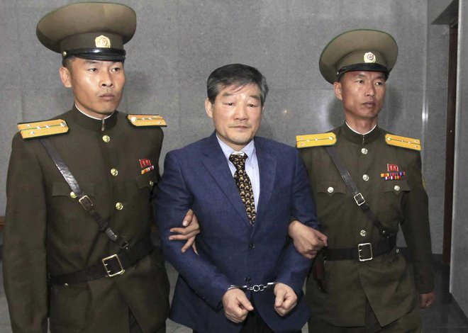 Enega izmed štirih ameriških državljanov, aretiranih v Severni Koreji, Kim Dong Čula, varnostniki vodijo na dosišče v Pjongjangu. FOTO: AP