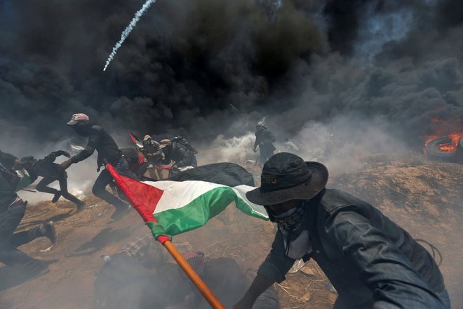 Na meji med Izraelom in Gazo so se v nebo dvigali oblaki črnega dima iz zažganih gum, proti izraelski vojski so letele molotovke in kamenje. Vojska je odgovorila s streljanjem, v katerem je umrlo najmanj 52 protestnikov, okoli 2400 je bilo ranjenih. Najbolj krvavi dan od vojne s Hamasom leta 2014. FOTO: Ibrahim Abu Mustafa/Reuters