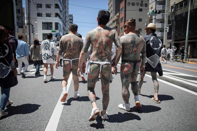 Jakuze s svojimi tradicionalnimi japonskimi tetovažami (irezumi), se sprehajajo po tokijskem okrožju Asakusa med letnim festivalom Sanja Matsuri. Tridnevni festival, ki ga obišče dva milijona Japoncev, je posvečen praznovanju treh ustanoviteljev templja Sensoji.&nbsp;FOTO: Behrouz Mehri/AFP